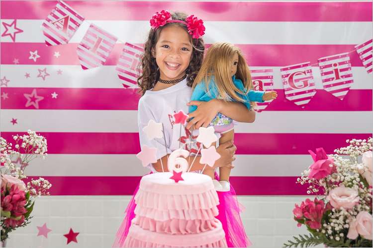 Девочка во время своего дня рождения на фоне праздничного баннера и торта